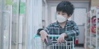 戴着面具的亚洲小孩走进超市买杂货