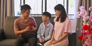 春节期间，一个亚洲小孩在客厅里接受父母的春节红包。