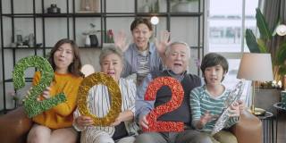 幸福亚洲多代2022年新年庆祝活动，亚洲家庭在客厅沙发上举行2022年文号与欢笑笑意欢畅的时刻，祖父母孙子父母坐在放松的沙发上