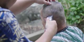 亚洲男子正在修剪亚洲高级男子头上的头发。