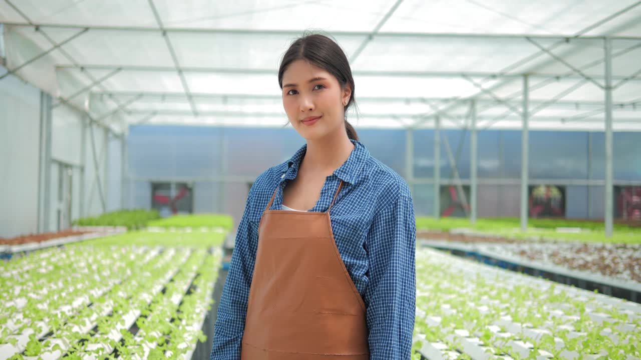现代水培蔬菜大棚农场里，亚洲女农主手挽着手，微笑幸福地望着镜头。