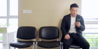 穿着商务正装的亚洲年轻人在等候室等待结果面谈或会议。在职男商人