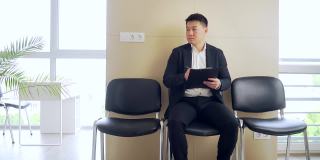 穿着商务正装的亚洲年轻人在等候室等待结果面谈或会议。在职男商人
