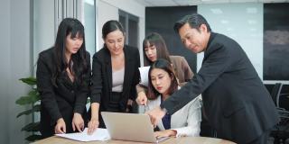亚洲业务团队在办公室看笔记本电脑演示，分享想法。商人分享他们的知识。