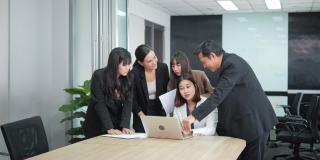 亚洲业务团队在办公室看笔记本电脑演示，分享想法。商人分享他们的知识。
