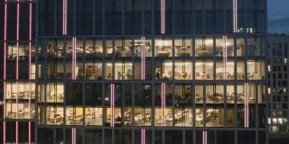 右边是在电脑前工作到很晚的办公室和商务人员在夜间摩天楼的窗户上拍摄的全景照片。