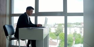 一个亚洲商人坐在办公室的电脑前工作