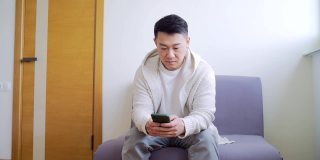 一个年轻的亚洲人坐在候诊室的走廊里等待面试或会议
