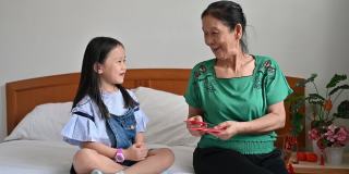 中国新年期间，亚洲孙女在卧室问候和接受祖母的中国新年红包