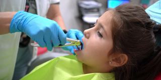 在一次拔牙时，勇敢的女孩坐在牙医的椅子上竖起大拇指
