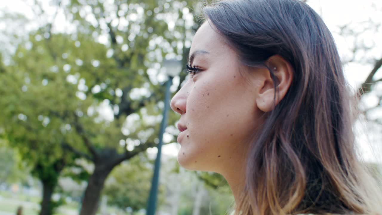 一段4k视频记录了一位美丽的年轻女子在公园散步时若有所思的样子