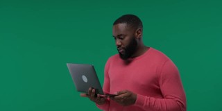 一个黑人惊喜地看到了他在绿色屏幕上的笔记本电脑，色度键