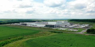 现代工厂的田野背景。广阔的工业疆域，绿荫蔽日，蓝天下。制造的正面视图。