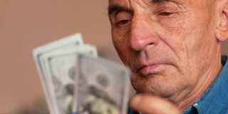 老年人与金融主题。一名70多岁的白人老人在数钞票。退休年龄，退休金分配。爷爷手里有美元。有选择性的重点,