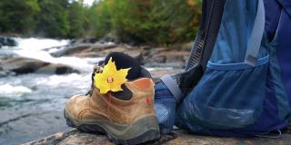 枫叶和加拿大国旗，河岸边徒步鞋，秋天加拿大徒步背景