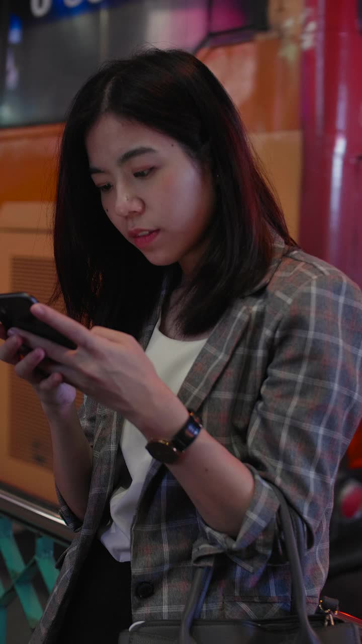 垂直视图:年轻的亚洲妇女在城市发短信手机