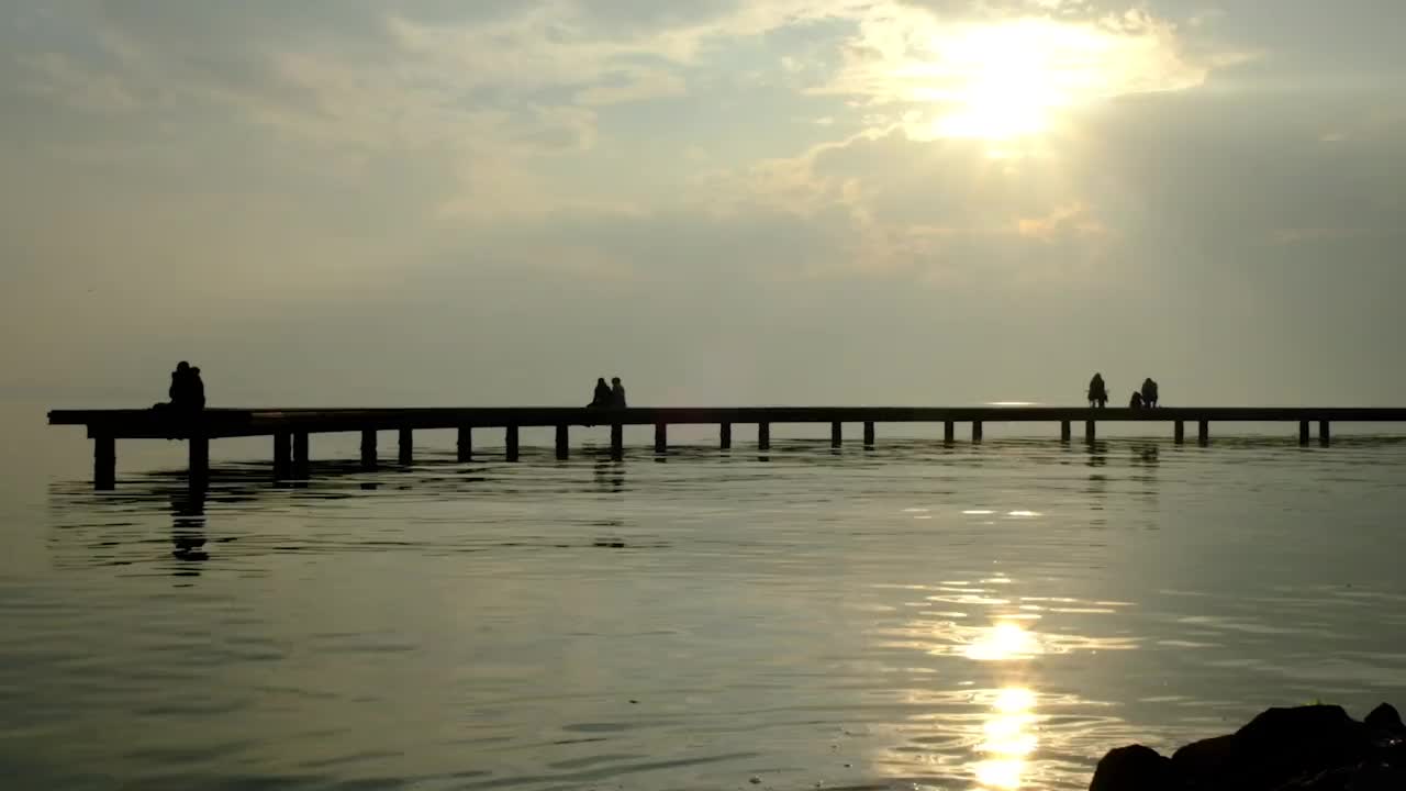 情侣们在码头上看日落。