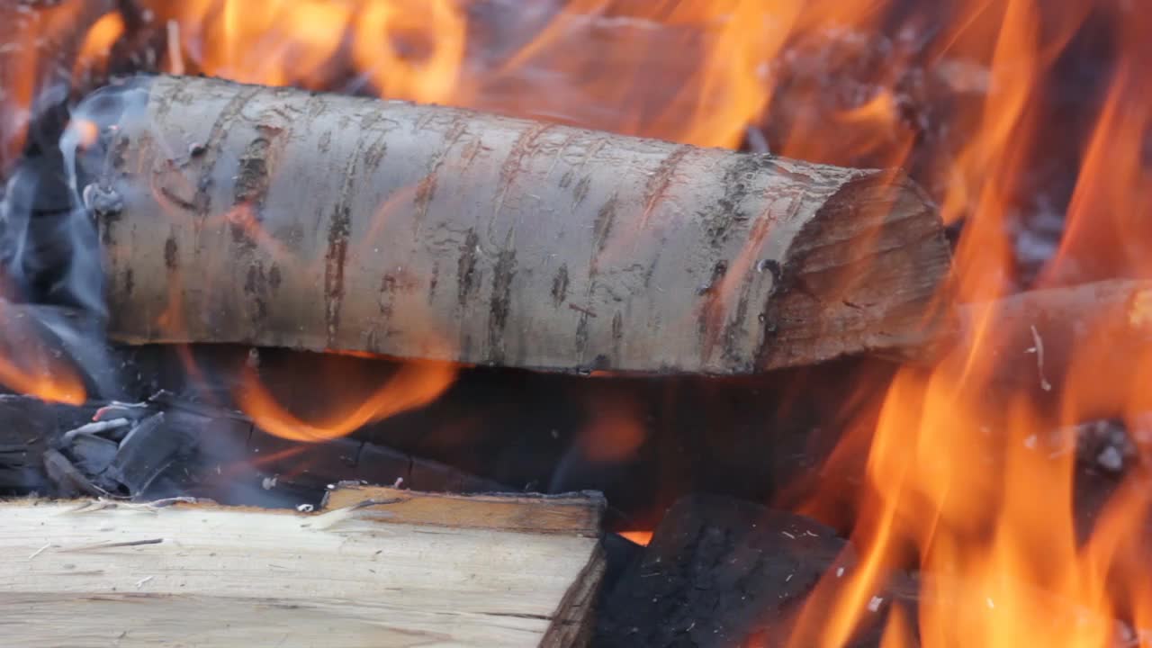 在最近点燃的火中燃烧着的木头。为烤架烧木柴