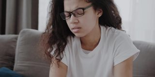 特写疲惫的非洲裔美国千禧一代妇女摘掉眼镜遭受偏头痛或头痛，不健康的疲惫的混血女性头晕或视力模糊在家里过度工作