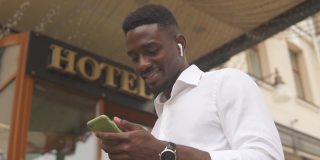 一名非洲裔美国人站在酒店外使用智能手机