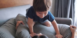 男孩在妈妈身上玩枕头。