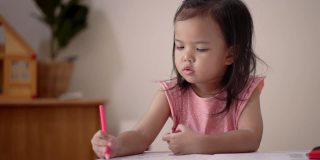 亚洲小女孩在家里用彩色铅笔涂色练习本学习