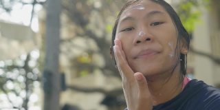 亚洲女孩在与家人在酒店或度假胜地度假前，在脸上和身体涂防晒霜，生活理念。