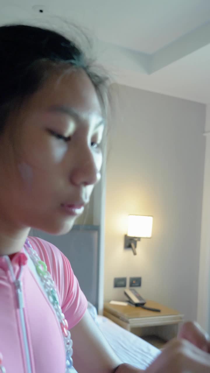 亚洲女孩在卧室里涂防晒霜，在她的脸和身体在游泳之前，与家人在酒店或度假村度假，生活方式的概念。
