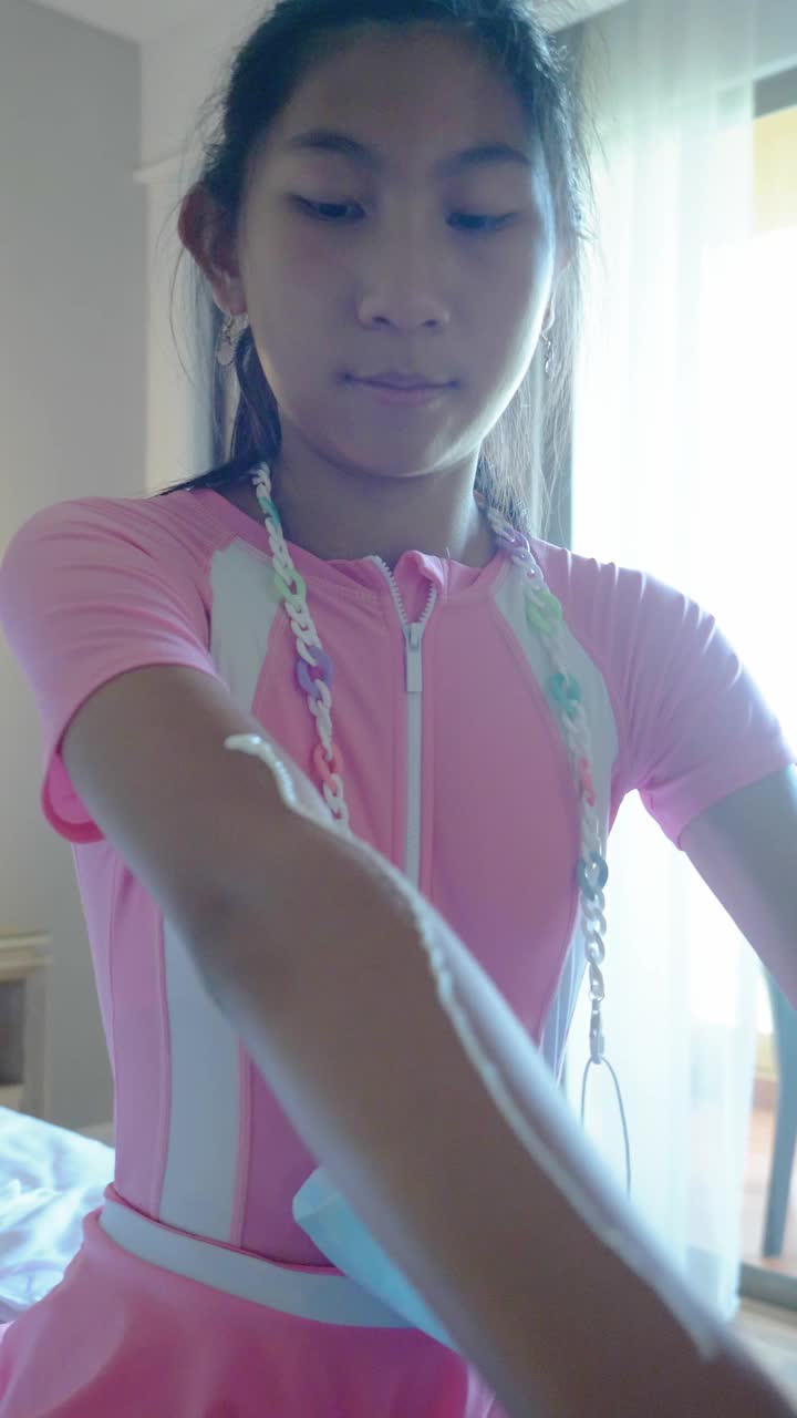 亚洲女孩在卧室里涂抹防晒乳液，在与家人在酒店或度假胜地度假前游泳，生活理念。
