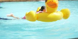 快乐的亚洲女孩在泳池玩黄鸭橡皮筏假期与家人，生活理念。