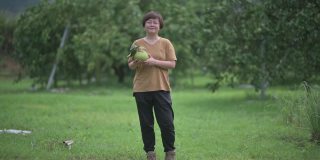 满意的亚洲中国女农民从果树采摘柚子在她的种植园收获看着相机微笑