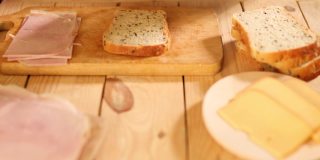 一个匿名的女人在木桌上用奶酪和火腿做美味三明治