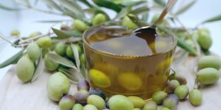 天然橄榄油在透明的碗里用勺子搅拌，里面有成熟的橄榄果，具有抗氧化保健和人体的有机产品，橄榄油用于美容