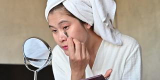 亚洲女性用化妆刷涂基础眼影。