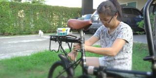 妇女安装自行车后儿童座位的自行车在前院的家
