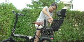 妇女安装自行车后儿童座位的自行车在前院的家