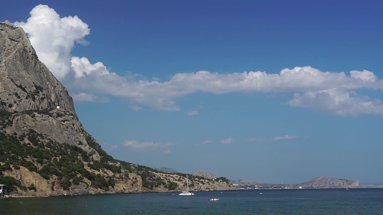 云层从岩石中出来，沿着高耸的悬崖环绕的美丽的海湾移动。旅行时欣赏自然美景(黑海、克里米亚、苏达克-里曼湾)