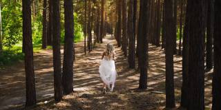 穿着婚纱和运动鞋的女子在森林中奔跑
