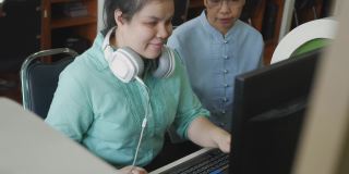 真实的盲人女性带着耳机使用电脑和盲文显示辅助装置与高级同事在工作场所讨论，手持拍摄。