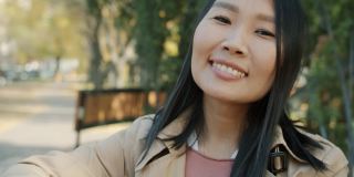 快乐的亚洲女孩的特写照片微笑着反对城市公园的背景