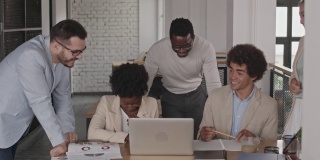 一群不同的商业同事在笔记本电脑上观看一段有趣的视频
