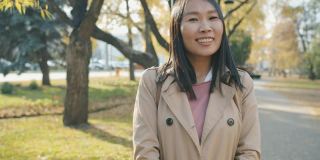 成功的亚洲女学生站在户外微笑看着相机的肖像