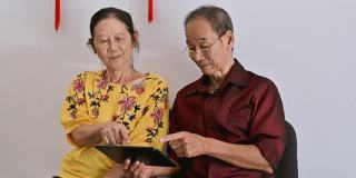 一对年长的亚洲夫妇用平板电脑网购迎接即将到来的中国新年