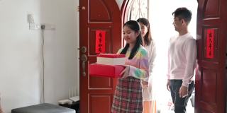 年轻漂亮的亚洲少女和父母在中国新年期间拜访她的亲戚家，赠送礼物和食物
