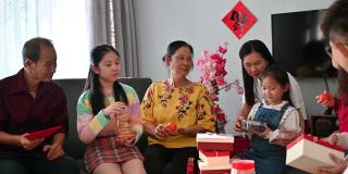 欢乐的亚洲家庭三代欢聚在客厅庆祝中国新年，享受传统美食