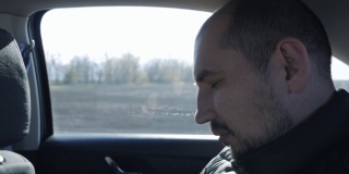 一个人在长途旅行中睡在一辆移动的汽车里。疲惫的乘客驾车旅行的肖像。旅行或度假概念