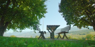 有桌子的木凳放在草地上，背对着山谷