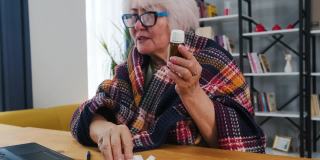 老年妇女边看边用笔记本电脑视频通话，在家在线医疗数字技术服务咨询