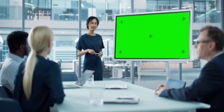 女运营经理为一组经济学家做会议报告。亚洲妇女使用数字白板水平绿色屏幕模拟显示。在商务办公室工作的人。