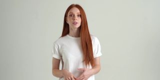 肖像自信漂亮的年轻女子说话和微笑看着相机，站在白色孤立的背景在工作室。